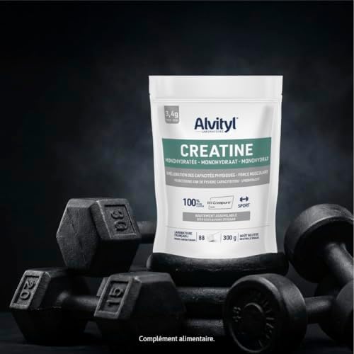 Sachet de créatine Alvityl posé sur une surface sombre, entouré de plusieurs haltères noirs de différentes tailles, évoquant l'univers de la musculation.