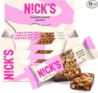 Une boîte ouverte de barres N!CK'S saveur cacahuète, avec plusieurs emballages individuels et deux barres déballées en premier plan, l'une entière et l'autre coupée en deux, révélant les cacahuètes et le chocolat.