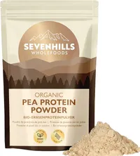 Un sachet refermable de poudre de protéines de pois bio Sevenhills Wholefoods, de couleur beige clair, est posé à côté d'un petit tas de la même poudre.