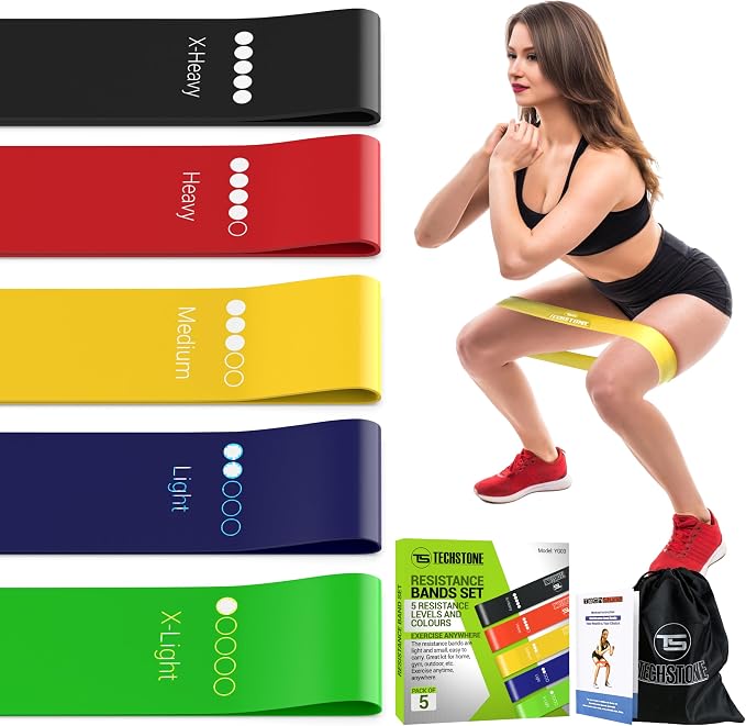 Un ensemble de cinq mini-bandes de résistance TechStone de couleurs différentes (noir, rouge, jaune, bleu, vert) avec leurs niveaux de résistance indiqués. À droite, une femme effectue un squat avec une bande jaune autour des cuisses. En bas, l'emballage du produit, un dépliant d'instructions et un sac de transport noir sont visibles.